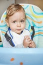 Funny expression of a cute baby child eating by itself and not liking the food Royalty Free Stock Photo