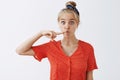 Funny expressive attractive blonde female student in vintage red polka-dot blouse and headband folding mouth in fish
