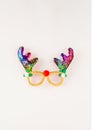 Funny eyeglasses with shape of the reindeer antlers made of colorful shiny tinsels on white background