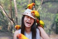 Funny face of beautiful Asian woman playing with sun conure parrots Royalty Free Stock Photo