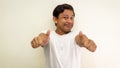 Funny face expression of young Asian Malay man in white t-shirt showing double thumbs up Royalty Free Stock Photo