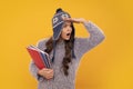 Funny face. Funny school girl child student with book and warn hat, isolated yellow background. Learning and knowledge