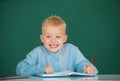 Funny face of little student of primary school study in classroom at school. Kid writing in notebook in class. Royalty Free Stock Photo