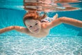 Funny face portrait of child boy swimming and diving underwater with fun in pool. Kid in the water swimming underwater Royalty Free Stock Photo