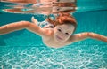 Funny face portrait of child boy swimming and diving underwater with fun in pool. Kid in the water swimming underwater Royalty Free Stock Photo