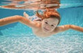 Funny face portrait of child boy swimming and diving underwater with fun in pool. Kid in the water swimming underwater Royalty Free Stock Photo