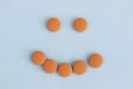 Funny faces of orange pills on a blue background. Concept of antidepressants