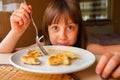 Funny facial expression of young beautiful girl eating cheesecakes for breakfast Royalty Free Stock Photo