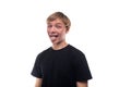 Funny fair-haired teenager guy in a black T-shirt shows his tongue