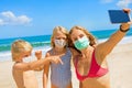 Funny family in face masks taking selfie photo on beach Royalty Free Stock Photo