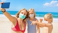 Funny family in face masks taking selfie photo on beach Royalty Free Stock Photo