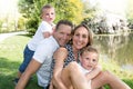 Funny family portrait of happy family of four in a green summer park aside lake river Royalty Free Stock Photo