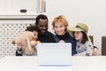 Funny family watching a laptop screen, mixed-race parents and children spend time with modern entertainment devices, watching