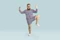 Funny happy chubby young guy in striped swimsuit and sunglasses dancing in studio Royalty Free Stock Photo
