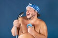 Funny fat man in blue cap sing in the shower Royalty Free Stock Photo