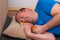 A funny fat man in a blue t-shirt sleeps after training hugging a bitten-off loaf. home fitness training, independent