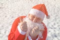 Funny fat man dressed as santa claus is sitting on the snow. Frosty winter and sunny day