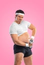 A funny fat man with dubbell isolated on pink background. Obesity and eating disorder. Concept for dietetics and fitness