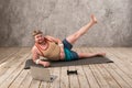 Funny fat man in sports clothes doing exercises. He plays sports remotely while looking at his laptop Royalty Free Stock Photo