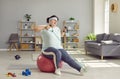 Funny fat woman sitting on fit ball at home and doing exercise with resistance band Royalty Free Stock Photo