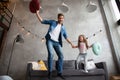 Funny father and cute kid daughter laughing jumping having fun in living room, active family enjoying moving playing