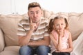 Funny father and daughter sitting on sofa at home