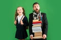 Funny father or teacher with school girl daughter hold big stack school textbook notebook books, isolated on green. Royalty Free Stock Photo