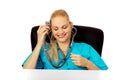 Funny female doctor or nurse sitting behind the desk with stethoscope Royalty Free Stock Photo