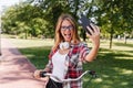 Funny female model posing in park with tongue out. Outdoor portrait of active girl on bicycle makin Royalty Free Stock Photo