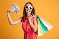 Funny female shopaholic holding fan of money and colorful shopping bags, looking at camera Royalty Free Stock Photo