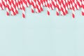 Funny festive bright abstract background - striped red cocktail straws on pastel candy mint color backdrop.