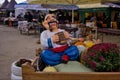 Funny figure of a colorful character, pumpkins and autumn flowers at an outdoor fair.