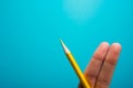 Funny fingers drawing holding yellow pencil against blue background. Conceptual motivation picture