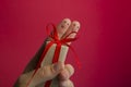 Funny fingers couple holding present gift box against red background with copy space for ad text. Happy family
