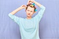 Funny focused young woman is putting her hair into colorful curlers Royalty Free Stock Photo