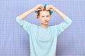 Funny focused young woman is putting her hair into colorful curlers Royalty Free Stock Photo