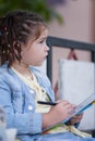 funny four-year-old girl with pigtails in a blue jacket is drawing