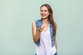 Funny freckled girl in casual white t shirt and jeans jecket, pointing finger at camera and toothy smile. Royalty Free Stock Photo