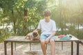 Funny french puppy bulldog and teenager playing games outside. Adorable orange bulldog in blue harness in the playground on sand. Royalty Free Stock Photo