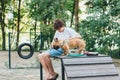 Funny french puppy bulldog and teenager playing games outside. Adorable orange bulldog in blue harness in the playground on sand. Royalty Free Stock Photo