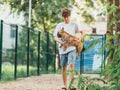 Funny french puppy bulldog and teenager playing games outside. Adorable orange bulldog in blue harness in the playground on sand. Royalty Free Stock Photo