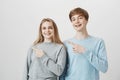 Funny friendly siblings showing direction to moms guest. Attractive brother and sister with fair hair, pointing left Royalty Free Stock Photo