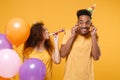 Funny friends couple african american guy girl in birthday hat isolated on yellow background. Holiday party concept Royalty Free Stock Photo