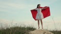 Funny and funny woman plays hero in a cloak of red cloak. girl dreams of becoming a superhero. beautiful superhero girl