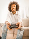 Funny gamer play computer games sitting alone at home in self isolation during quarantine period. Young Arabic guy holds