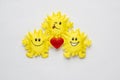 Funny flock of smiling holiday toy sun with a red heart on a white background