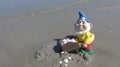 Funny garden dwarf with wheelbarrow on the beach