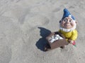 Funny garden dwarf with wheelbarrow on the beach