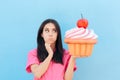 Funny Girl with Big Cupcake Thinking of her Diet Royalty Free Stock Photo