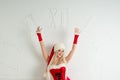Funny girl in Christmas outfit points to watch. Red Santa suit with hood. Royalty Free Stock Photo